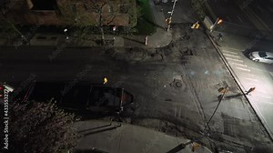 Time-lapse of a city street being paved with fresh asphalt during the night.